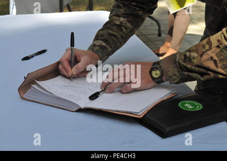 KABUL, Afghanistan (Sept. 9, 2015) ein service Mitglied meldet ein Gedenkbuch für Corey Dodge nach einer Zeremonie zu Ehren sein Opfer zum Schutz detail für das Beraterteam der afghanischen nationalen Armee und der afghanischen nationalen Polizei im Rahmen der NATO-geführten Mission der entschlossenen Unterstützung. Dodge, Richard McEvoy und Barry Sutton, zivile Auftragnehmer von DynCorp International, starb bei einem Angriff auf ihren Konvoi 12.08.22 in Kabul. Die trauerfeier an der Destille Garten gehalten wurde mit diesen zahlen ihren Respekt einschließlich Führungskräfte von der entschlossenen Unterstützung der US-Botschaft - Kabul, DynCorp Inte Stockfoto