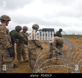 Us-Armee Fallschirmjäger zu Hund Unternehmen, 1.BATAILLON, 503Rd Infanterie Regiment, 173Rd Airborne Brigade zugeordnet, lernen Sie von Litauischen Landstreitkräfte Ingenieure aus der allgemeinen Ingenieur Coy, Juozas Vitkus Engineer Battalion, wie man am besten eine Ziehharmonika draht zaun zu bauen Angriff gegen die Struktur, die sie verteidigen, während am zweiten Tag der Übung Ingenieur Donner wurden zur Abschreckung an der Großen Litauischen Hetman Jonusas Radvila Training Regiment, in Rukla, Litauen, Sept. 9, 2015 statt. Die Soldaten der 173Rd Airborne Brigade werden in Europa als Teil der Atlantischen lösen, eine Demonstration der anhaltenden US-commitme Stockfoto