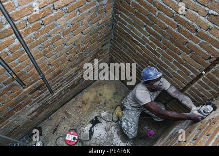 Us-Armee SPC. Chris Lake, ein Louisiana nationalen Scots Guards Plummer von 1020Th Ingenieur Unternehmen, Schnitzen von Nuten in Backstein mit einem Schleifer zu Inlay PVC-Rohrleitungen während einer Schule neben der Operation Keris Streik bauen, Pacific Pathways 2015 Tai Ping, Malaysia, an Sept. 9, 2015. Betrieb Keris Streik ist eine regelmäßig geplante bilaterale Übung gesponsert von US-Army-Pacific, gehostet, die jährlich durch die Tentera Darat Malaysia regionale Sicherheit, Unterstützung und Zusammenarbeit zu fördern. (U.S. Armee Foto von SPC. Michael Sharp / freigegeben) Stockfoto