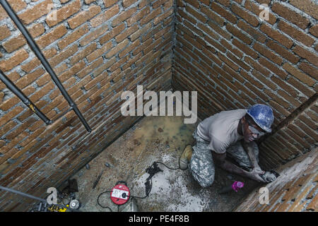 Us-Armee SPC. Chris Lake, ein Louisiana nationalen Scots Guards Plummer von 1020Th Ingenieur Unternehmen, Schnitzen von Nuten in Backstein mit einem Schleifer zu Inlay PVC-Rohrleitungen während einer Schule neben der Operation Keris Streik bauen, Pacific Pathways 2015 Tai Ping, Malaysia, an Sept. 9, 2015. Betrieb Keris Streik ist eine regelmäßig geplante bilaterale Übung gesponsert von US-Army-Pacific, gehostet, die jährlich durch die Tentera Darat Malaysia regionale Sicherheit, Unterstützung und Zusammenarbeit zu fördern. (U.S. Armee Foto von SPC. Michael Sharp / freigegeben) Stockfoto