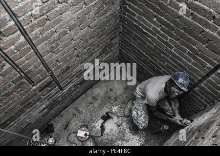 Us-Armee SPC. Chris Lake, ein Louisiana nationalen Scots Guards Plummer von 1020Th Ingenieur Unternehmen, Schnitzen von Nuten in Backstein mit einem Schleifer zu Inlay PVC-Rohrleitungen während einer Schule neben der Operation Keris Streik bauen, Pacific Pathways 2015 Tai Ping, Malaysia, an Sept. 9, 2015. Betrieb Keris Streik ist eine regelmäßig geplante bilaterale Übung gesponsert von US-Army-Pacific, gehostet, die jährlich durch die Tentera Darat Malaysia regionale Sicherheit, Unterstützung und Zusammenarbeit zu fördern. (U.S. Armee Foto von SPC. Michael Sharp / freigegeben) Stockfoto