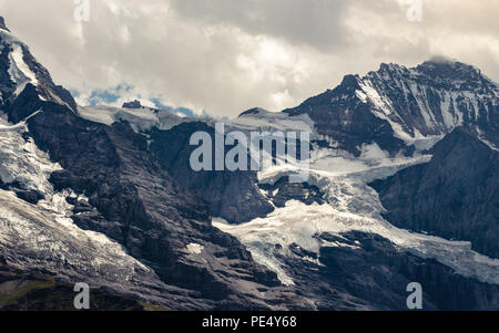 Blick auf das Jungfraujoch mit Sphinx obervatory (3454 m/11.371 ft) und Jungfrau Peak (4158 m/13.642 ft) unter dramatischen bewölkter Himmel im Sommer, Berner Al Stockfoto