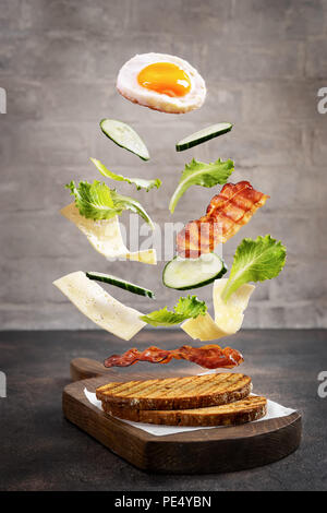 Flying Zutaten für das Frühstück sandwich über Holz Schneidebrett Stockfoto