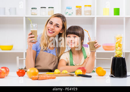 Glückliche Mutter und ihrer Tochter genießen Sie machen und trinken Smoothies zusammen an ihrem Haus. Stockfoto