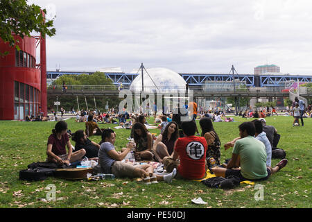 Paris Park - Menschen entspannend auf Gras der Park La Villette mit Blick auf Spiegel- dome La Géode, Paris, Frankreich, Stockfoto