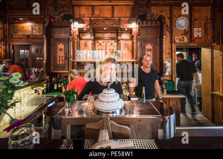 Blonde Frau und Mann hinter der Theke in der herrlichen Speisesaal der Berghütte Berliner Hütte lächeln in die Kamera, Zillertal, Österreich Stockfoto