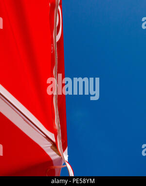 Farbe in der Nähe eines roten Sonnenschutz Schuß von unten gegen ein strahlend blauer Himmel Stockfoto