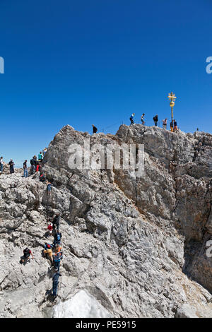 Touristen klettern Zum Goldenen Kreuz - der höchste Punkt in Deutschland auf dem Gipfel der Zugspitze mit 2962 m über dem Meeresspiegel Stockfoto