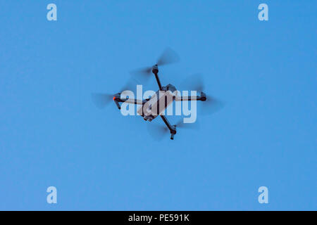 Schwarz Kamera Drohne im Flug mit sichtbaren Propeller Bewegung und Blitzleuchte und blauer Himmel. Stockfoto