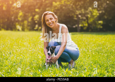 Schöne Frau genießt die Zeit in der Natur mit ihren niedlichen Hund Jack Russell Terrier. Bild ist absichtlich abgeschwächt. Stockfoto