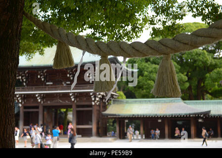 Ein shimenawa, oder Stroh Seil mit Armreifen und weiß Zickzack Papierstreifen, hängt zwischen zwei Bäumen innerhalb der Meiji-schrein in Tokyo, Sept. 10, 2015. In der Shinto Religion, Shimenawa sind Indikatoren dafür, dass etwas Heiliges ist. (U.S. Air Force Foto von Airman 1st Class Elizabeth Baker/Freigegeben) Stockfoto