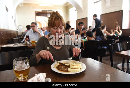 Frau mit Glas der traditionellen klassischen tschechischen Bier und Essen im Lokal Dlouhaaa Bier Pub Restaurant in Prag, Tschechische Republik Stockfoto