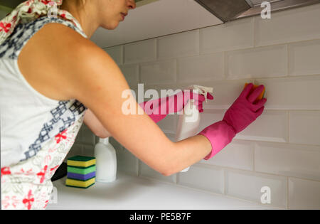 Frau Reinigung Küche Fliesen mit Spray Reiniger und Schwamm. Hausrat, Reinigung, aufräumen, Reinigung Service Konzept. Stockfoto