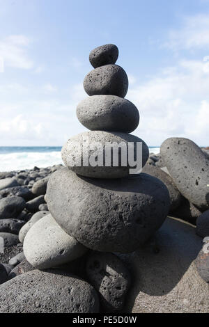 Gestapelte Steine oder Kieselsteine am Strand mit der blauen Himmel im Hintergrund. Stockfoto