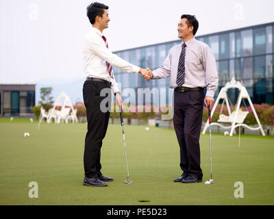 Zwei asiatischen Führungskräfte Hände schütteln nach Golfspielen auf der Dachterrasse. Stockfoto