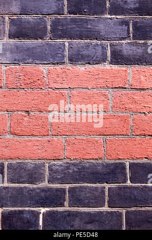 Brick Wall schwarz lackiert und orange Hintergrund. Textur, Architektur. Stockfoto