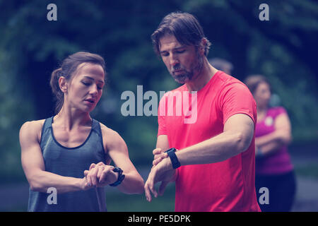 Junge sportliche Paar mit smart Uhren beginnen, ihre Timer vor dem Joggen Stockfoto
