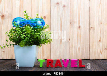 Reisen Buchstaben text und Notebook Papier, Wecker und wenig Deko Baum in weiße Vase auf hölzernen Hintergrund, Reise Urlaub Konzept Idee. Stockfoto