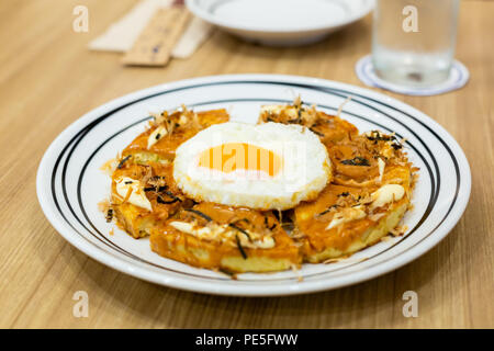 Okonomiyaki, Japanische Pizza auf dem Holztisch. Stockfoto