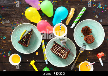 Schokolade Kuchen und Dekoration Party auf braune Holztisch flach. Ansicht von oben Kinder geburtstag Tabelle mit festlichen Essen Stockfoto