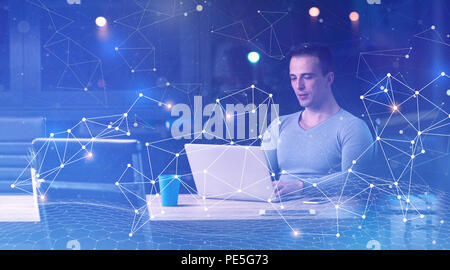 Junger Mann nachts im dunklen Büro am Laptop arbeiten. Der Designer arbeitet in der späteren Zeit. Stockfoto