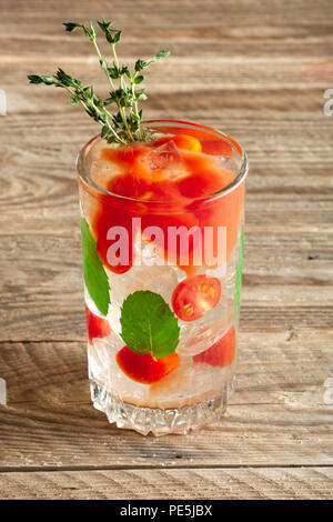 Cocktail mit Wodka, Tomaten, Minze und Eiswürfel auf hölzernen Tisch Stockfoto