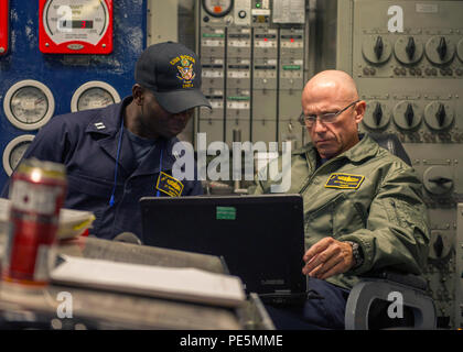 Elektrooffizier und Chefingenieur an Bord der USS Boxer (LHD 4) überprüfen die Schaltpläne auf einem Laptop im vorderen Maschinenraum, während das Schiff am 25. September 2015 vor Südkalifornien unterwegs ist. Boxer führt technische Prüfungen, Überwachung der elektrischen Systeme, Routinewartung und Schulung für den amphibischen Betrieb durch. Die Besatzung sorgt für Antrieb, Leistungsverteilung und Maschinenbereitschaft bei der Vorbereitung auf den Einsatz. Koordinierung und operative Aufsicht sorgen für die Bereitschaft zu Expeditionsstreiks der Gruppe 3. Stockfoto