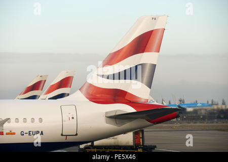 Reihe der Schwanzflosse von British Airways Airbus Jets vor dem Terminal 5 am Flughafen London Heathrow geparkt Stockfoto