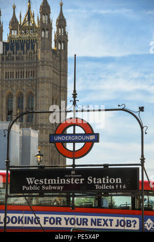 Schild über dem Eingang zum U-Bahnhof Westminster in London, mit der Suche nach Ihrem nächsten Job Nachricht an der Seite eines roten Bus im Hintergrund. Stockfoto