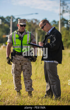 Sgt. Jerrod Ballard mit der Provost Marshal Office Gespräche mit einem Forscher während dringende Antwort 2015 auf die Marine Corps Base Camp Lejeune Okt. 7. Dringende Antwort ist eine jährliche, umfassende Übung entworfen, um zu prüfen, und Basis Rettungsdienst Zug reagieren zu einer großen Krise Incident, welche simuliert ein Fahrzeug - getragene Improvised Explosive Device und enthalten die Zusammenarbeit der Rettungsdienste auf, um mit der Installation zu schließen Feuer und Polizeidienststellen, Emergency Operations Center und Naval Hospital Camp Lejeune. (U.S. Marine Corps Foto von Lance Cpl. Ned Johnson/Freigegeben) Stockfoto