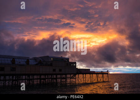 Aberystwyth Wales UK, Sonntag 12 August 2018 Großbritannien Wetter: Dunkel brütende und stürmischen Himmel über Aberystwyth Pier bei Sonnenuntergang, am Ende eines Tages des schweren Duschen und Zauber von strahlendem Sonnenschein Foto © Keith Morris/Alamy leben Nachrichten Stockfoto