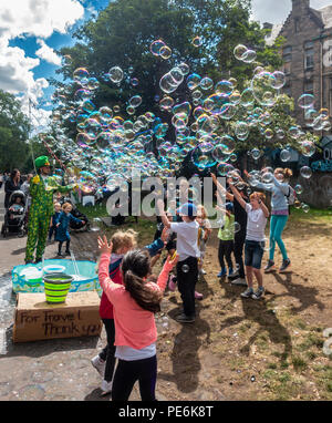 Street artist Freakbubbles, unterhaltsame Kinder mit Massen von Blasen in der Mitte der Wiese gehen, Edinburgh, beim Edinburgh Festival Fringe. Stockfoto