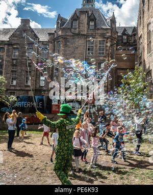 Street artist Freakbubbles, unterhaltsame Kinder mit Massen von Blasen in der Mitte der Wiese gehen, Edinburgh, beim Edinburgh Festival Fringe. Stockfoto