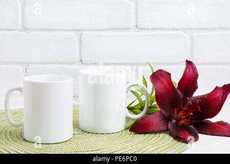 Zwei weiße Kaffeetasse mockup mit dunklen Burgund Lily. Leere Becher mock up für Design Promotion. Stockfoto