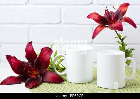 Zwei weiße Kaffeetasse mockup mit ein paar dunklen Burgund Lily. Leere Becher mock up für Design Promotion. Stockfoto