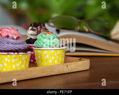 Bunte hausgemachte Kuchen auf Holz- Fach auf offenen Buch auf Holztisch und. Konzept der Lebensstil und Entspannen. Stockfoto