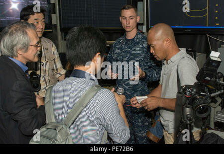 151013-N-YD 641-140 Yokosuka, Japan (Okt. 2010) 13, 2015) Air Traffic Controller 2. Klasse Michael Schwarm, von Myrtle Point, Erz, erklärt Flugbetrieb in Air Operations Center an Bord der US-Navy ist nur Vorwärts - bereitgestellt Flugzeugträger USS Ronald Reagan (CVN 76). Ronald Reagan und seine eingeschifft Air Wing, Carrier Air Wing (Cvw) 5, eine Bekämpfung bereit, Kraft, schützt und verteidigt die kollektive maritime Interessen seiner Verbündeten und Partnern in der Indo-Asia-Pazifik-Region. (U.S. Marine Foto von Mass Communication Specialist Seaman Matthew Riggs / freigegeben) Stockfoto