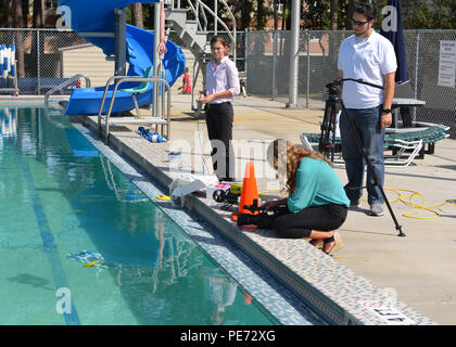 151008-N-TI 693-014 NAVAL SUPPORT ACTIVITY PANAMA CITY, Fla (Okt. 2010) 8, 2015) Kinsey Naud (links), ein Elektroingenieur mit dem Naval Surface Warfare Center Panama City Division (PCD), NSWC demonstriert die SeaPerch System, indem Sie die Navigation Ringe an der Unterseite der Basisstation pool zu sammeln, während mit Nachrichten Kanal 7 WJHG in Panama City Brianna DiPilato, befragt. Das Interview wurde für eine Nachrichten Geschichte über NSWC PCD der Stammzellen (Wissenschaft, Technologie, Ingenieurwesen und Mathematik) Outreach Programm mit einem System namens SeaPerch. (U.S. Marine Foto von Mass Communication Specialist 2. Klasse Fred Grau IV Stockfoto