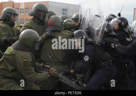 Deutsche Soldaten der multinationalen Battle Group-East Forward Command Post als widerspenstige Randalierer in einer Menschenmenge riot control Übung während des Betriebs Stonewall, 16. Okt. 2015, außerhalb der Bill Clinton Sportzentrum in Ferizaj, Kosovo zugewiesen. Betrieb Stonewall war eine kombinierte Notfalltraining Veranstaltung, die eine Masse riot control Situation übernommen, die von der Polizei des Kosovos und KFOR-Soldaten hielten zu MNBG zugeordnet - E. Die Übung mehr als 350 Mitarbeiter aus über mehrere Agenturen integriert als eine Möglichkeit, ihre Fähigkeit, eine sichere Umwelt durch das combin zu Praxis Stockfoto