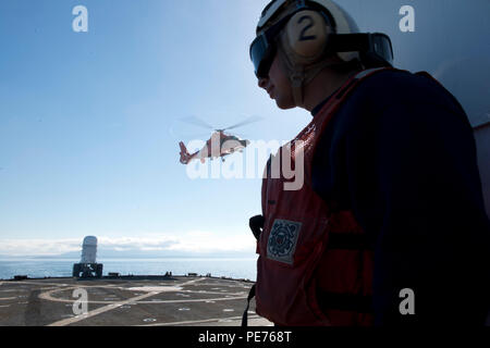 Einem MH-65 Dolphin helicopter Crew, von der Coast Guard Air Station Port Angeles, zieht aus der Flight Deck der Coast Guard Cutter Midgett, einem 378 Meter hohen - endurance Cutter in Seattle homeported, während einer laufenden Ausbildung Evolution in der Straße von Juan de Fuca, Okt. 13, 2015. Sowohl der Air Crew und Cutter crew profitierte von der gemeinsamen Ausbildung während mehrerer Entwicklungen der Anlandung, Abheben, Tanken und tieing nach unten. (U.S. Coast Guard Foto von Petty Officer 1st Class Levi lesen) Stockfoto