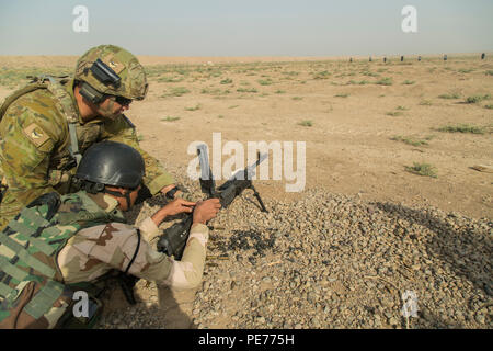 Eine australische Soldaten, zugeordnet zu den Task Group Taji, unterstützt ein irakischer Soldat seine Waffe während einer M249 Light Machine Gun Training am Schießstand im Camp Taji, Irak, am Okt. 14, 2015. Die Ausbildung wurde gehalten, um irakische Soldaten zu unterstützen, die 71 irakischen Armee Brigade, belegt mit Ihren neu ausgegebenen Waffen vertraut als Teil einer 9-wöchigen Schulung zu werden. (U.S. Armee Foto von SPC. William Marlow/Freigegeben) Stockfoto