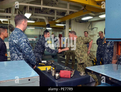 151027-N-WZ 747-143: POLARIS, Guam (Okt. 27, 2015) Maschinen Handwerker First Class (SW) David Sams, Mitte-links, ein Seemann, der zum U-Boot Tender USS Frank Kabel zugewiesen (40), grüßt der Adm. John Nowell, Commander, Expeditionary Strike Group 7, während einer Tour des Schiffes Maschinenhalle, Okt. 27. Nowell besucht Frank Kabel mit Matrosen zu treffen und erfahren Sie mehr über Reparatur und Wartung der Flotte angeboten. Frank Kabel, sich auf der Insel Guam eingesetzt, führt die Wartung und den Support von U-Booten und Überwasserschiffen in die USA 7 Flotte Bereich bereitgestellt Stockfoto