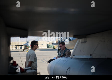 Kapitän Tyler McBride, rechts, 421St Expeditionary Jagdgeschwader Chef der Sicherheit, bereitgestellt von der Hill Air Force Base, Texas, geht über Pre-flight Schreibarbeit mit Airman 1st Class Christian Lamm, 455Th Expeditionary Aircraft Maintenance Squadron Crew Chief, von Aviano Air Base, Italien eingesetzt, in Bagram Air Field, Afghanistan, Okt. 30, 2015. Die 36Th EFS, bereitgestellt von Aviano Air Base, Italien, nähert sich dem Ende der sechsmonatigen Einsatz in Bagram und die Zügel in die Hand 421st EFS zur Unterstützung der Operation, die die Freiheit des Sentinel und der entschlossenen Unterstützung der NATO-Mission. (U.S. Air Force Foto b Stockfoto