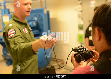 Leutnant Matthew Smith, einem MH-65 Dolphin Helikopter Pilot bei Air Station Friseure, demonstriert die Verwendung von Night Vision Goggles, die den Studenten in den Bereichen Wissenschaft, Technologie, Ingenieurwesen und Mathematik Exposition bei Coast Guard Base Honolulu, 15. Oktober 2015 teilnehmenden. Bei der Veranstaltung werden mehr als 100 Jugendliche aus Oahu Schulen gedreht bis 10 Stationen über Stammzellen - Ähnliche Karrierechancen zu erfahren. (U.S. Coast Guard Foto von Petty Officer 3. Klasse Melissa E. McKenzie/Freigegeben) Stockfoto