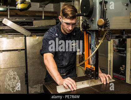 151019-N-ZZ 999-076 GEWÄSSER SÜDLICH VON JAPAN (23. 19, 2015) der Luftverkehr strukturellen Mechaniker 3. Klasse Alexander Taschner, von Palmdale, Calif., verwendet eine Bandsäge Winkel Eisen in die flugzeugzelle Shop an Bord der US-Navy ist nur vorwärts zu schneiden - bereitgestellt Flugzeugträger USS Ronald Reagan (CVN 76). Ronald Reagan und seine eingeschifft Air Wing, Carrier Air Wing (Cvw) 5, eine Bekämpfung bereit, Kraft, schützt und verteidigt die kollektive maritime Interessen seiner Verbündeten und Partnern in der Indo-Asia-Pazifik-Region. (U.S. Marine Foto von Mass Communication Specialist 3. Klasse James Lee/Freigegeben) Stockfoto