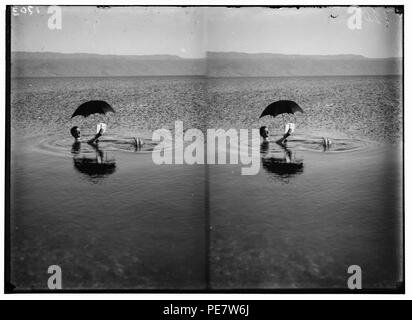 Um das Tote Meer. Mann floating mit Buch und Regenschirm in der Hand Stockfoto