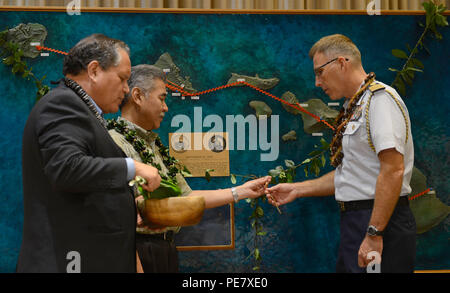 Kahu Kelekona Bishaw führt David Ige, Hawaii State Gouverneur und Kapitän James Jenkins, Coast Guard 14. Bezirk Stabschef, durch eine feierliche Segnung der Geist des laulima durch eine Partnerschaft zwischen Hawaii und die Küstenwache nach Bekanntgabe der Fertigstellung des Anuenue Interisland digitale Mikrowelle Netzwerk vertreten zu bestätigen, an der Hawaii State Capitol in Honolulu, Okt. 22, 2015. Der IDMN Anuenue besteht aus hoher Kapazität Mikrowelle links, Radio Türme und Gebäude, die miteinander verbunden sind und die Systeme und Netzwerke von Ersthelfern verlassen, s Stockfoto