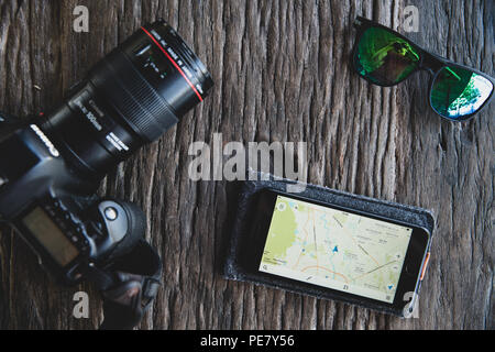 Ansicht von oben Zubehör touristische Mann Planung Reisen mit Mobiltelefon, Kamera, Sonnenbrille auf Holztisch. Sommer Urlaub und Reisen Konzept. Stockfoto