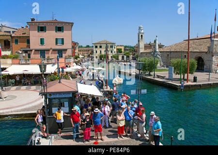 Touristen warten auf eine Anlegestelle für die Fähre, die Hafeneinfahrt von Lazise, Gardasee, Provinz Verona, Italien Stockfoto