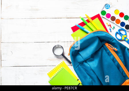 Schule Bildung Hintergrund. Schule Rucksack mit Schreibwaren auf weissem Holztisch. Ansicht von oben mit der Kopie. Stockfoto